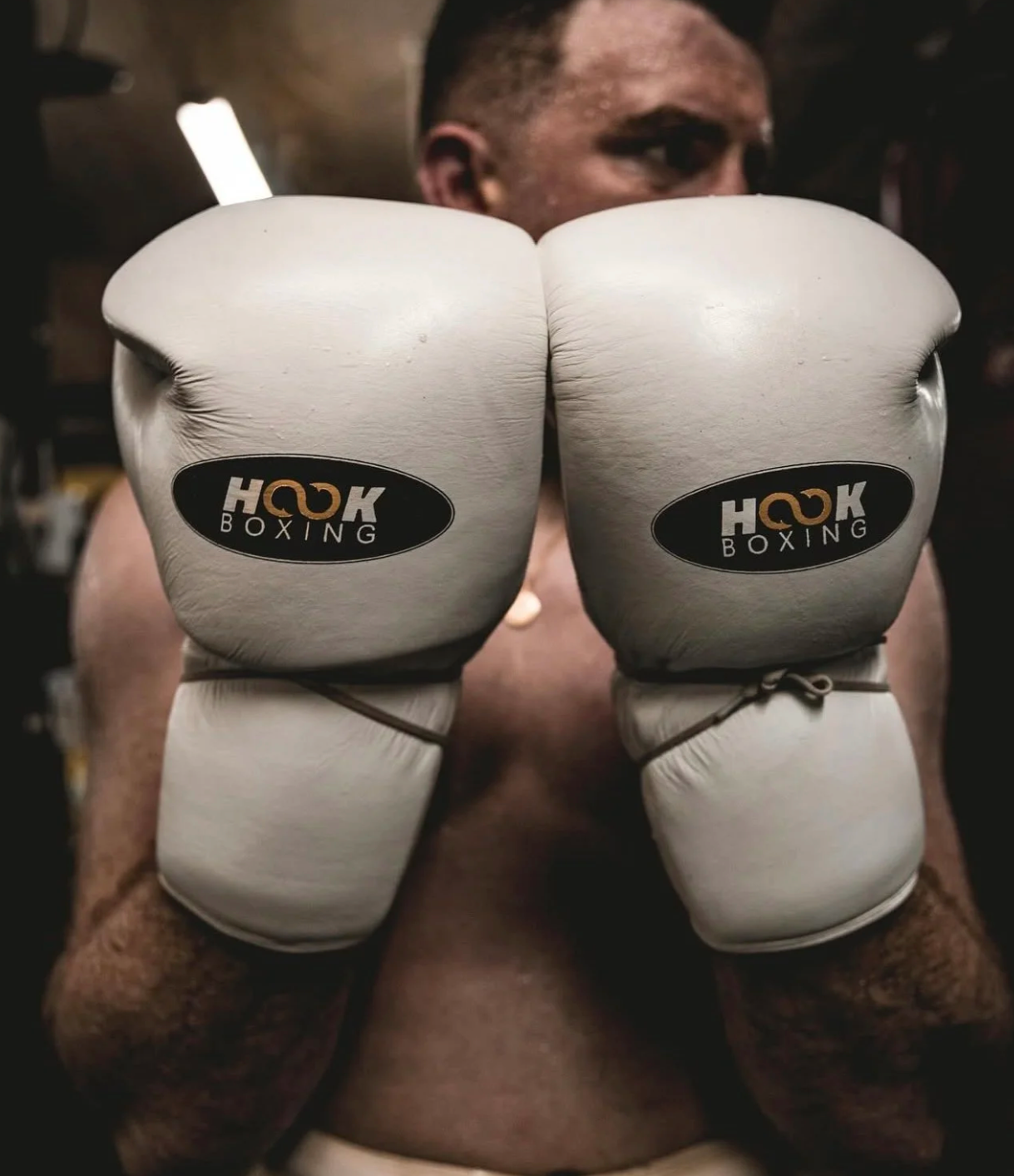Person wearing white boxing gloves with 'Hook Boxing' branding.